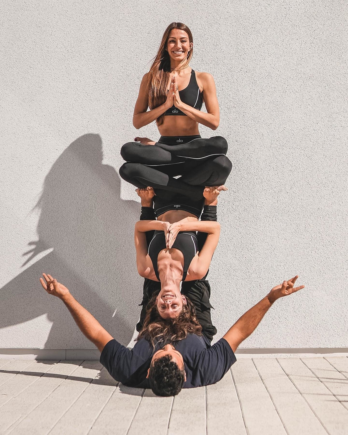 @tawnyjanae @acrowithjon and @ itscaitlinturner performing acro yoga wearing all black yoga Alo sets.