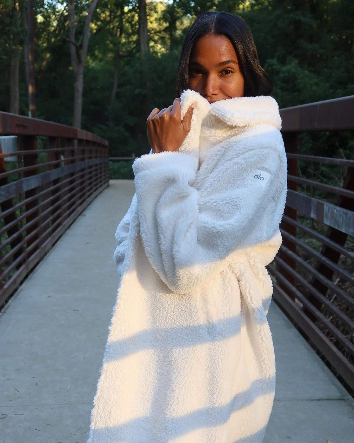 @arlenissosa wearing the Oversized Sherpa Trench in Ivory while walking across a bridge outside.