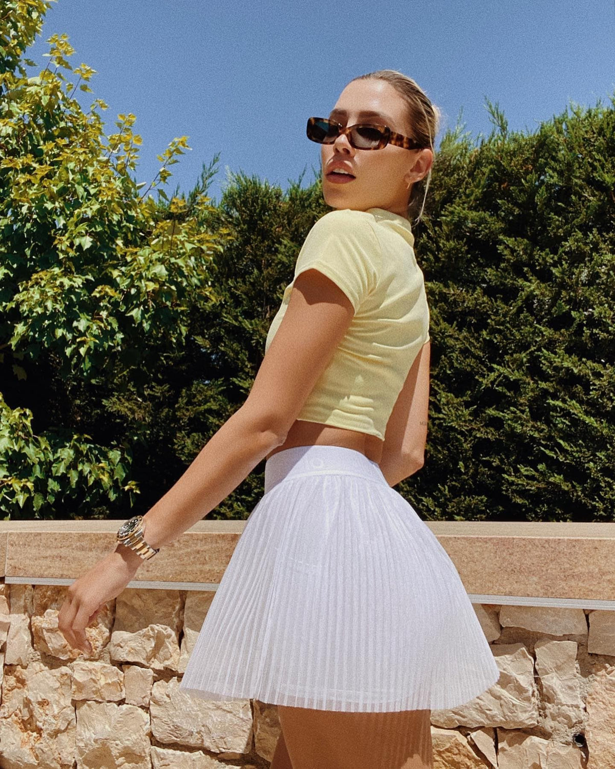 @michellesalasb wearing a Mesh Flirty Tennis Skirt in White with a Choice Polo in Buttercup while posing outside.